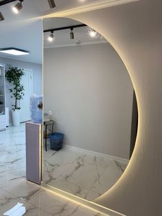 a large mirror in the middle of a room with white walls and marble flooring