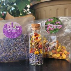 a jar filled with dried flowers sitting on top of a table next to two bags