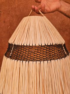 a hand holding a piece of straw with black lines on it and the end of a large umbrella