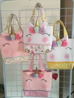 four unicorn bags hanging on a wire rack in a room with other purses and handbags