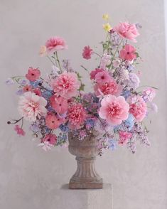 a vase filled with pink and purple flowers on top of a white countertop next to a wall