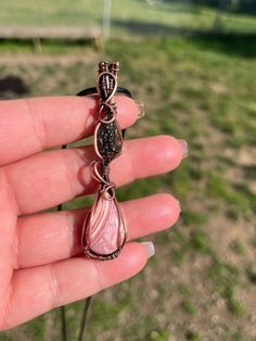 Wire wrapped Moldavite and Rhodochrosite pendant in oxidized copper wire 🤍 This beautiful piece was hand picked, made with love💗 Moldavite is the ultimate stone of transformation. It is a tektite. Known for bringing about shifts in energy, encouraging us to face negative thoughts and feelings and unleashes us from past traumas so we can move forward in life stronger. 💚✨  Rhodochrosite is known to bring feelings of compassion, deeper emotional connections, and openness to love without judgment or expectations ️ Thanks for your support! 🥰 Every pendant comes with a 18' black cord adjustable clasp necklace to fit all necks 💛 Pink Wire Wrapped Copper Jewelry, Pink Wire Wrapped Copper Wire Jewelry, Pink Copper Wire Wrapped Jewelry, Wire Wrapped Crystal, Wrapped Crystal, Boho Crystal, Oxidized Copper, Wire Wrapping Crystals, Clasp Necklace