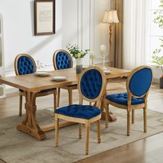 a dining room table with blue chairs and a white rug on the floor in front of it