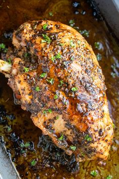 a close up of a piece of chicken in a pan with sauce and parsley