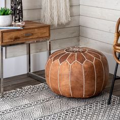 a brown ottoman sitting on top of a rug next to a wooden table and chair