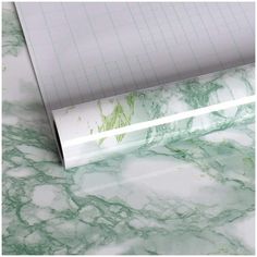 a marble counter top with green and white designs on the surface, next to a ruler