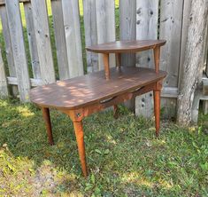 two wooden tables sitting in the grass next to a fence