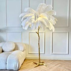 a large white feather lamp on a wooden floor next to a couch and chair in a room