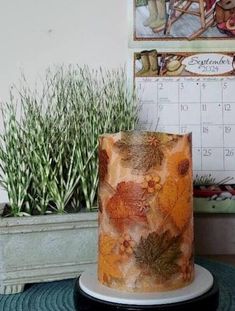 a decorated cake sitting on top of a table next to a calendar and potted plants