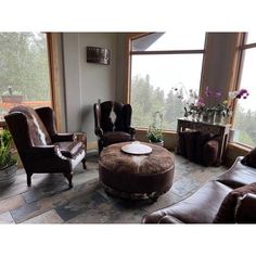 a living room filled with lots of furniture and large windows overlooking the trees in the distance