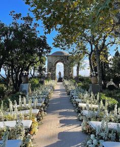 an outdoor ceremony set up with white flowers and greenery on the ground, surrounded by trees