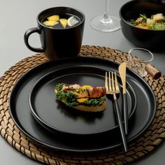 a black plate topped with food next to two cups