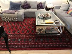 a living room filled with lots of furniture and pillows on top of a red rug