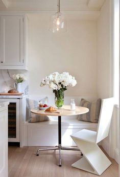 a kitchen with white cabinets and flowers on the table