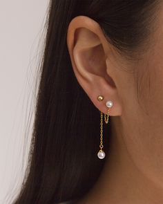 a close up of a person wearing gold ear chains and earrings with pearls on them