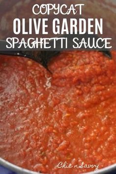 a pot filled with red sauce sitting on top of a blue table cloth next to a black spatula