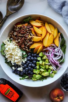 a white bowl filled with fruit, nuts and other vegetables next to an orange juice