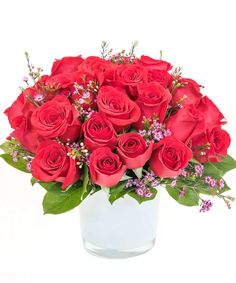 a vase filled with red roses and greenery