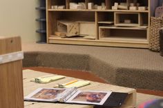 an open book sitting on top of a wooden table next to a shelf filled with books