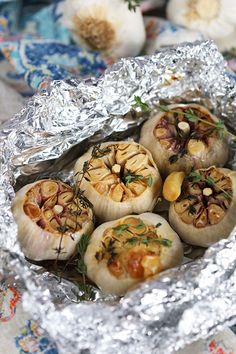 some food is sitting on tin foil in the middle of a table with garlic and other vegetables