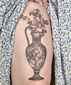 a woman's thigh with a vase and flowers on it