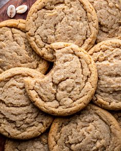 a pile of cookies sitting on top of a wooden cutting board next to some nuts