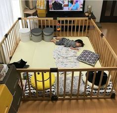 a small child laying on top of a bed in front of a tv