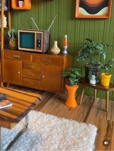 a living room with green walls and wooden furniture in the corner, including an old tv