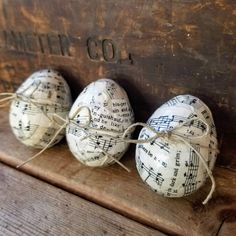 three decorated eggs sitting on top of a wooden box with sheet music notes painted on them