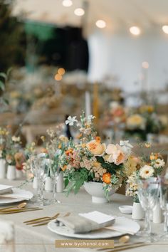 the table is set with white plates and silverware, flowers in vases, and candles