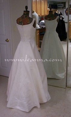 two wedding gowns on mannequins in front of a mirror