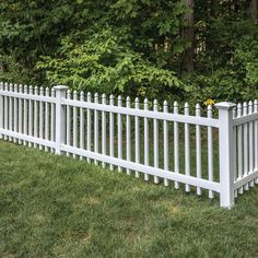 a white picket fence in front of some trees