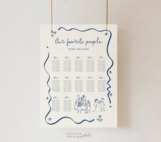 a blue and white wedding seating chart hanging on a string with two people standing next to each other