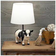 a cow figurine sitting on top of a wooden table next to a lamp