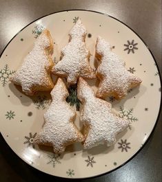 a white plate topped with cut up cookies covered in powdered sugar and decorated with snowflakes