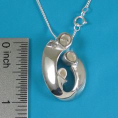 "Mother of two children pendant may also be interpreted as celebrating your family of three! Our expressive, egg-shaped creation is hand sculpted in sterling silver. Size: 1\" X 3/4\": $145. Bright polished heads and raised curves are contrasted with recessed contours that have a soft satin finish. Fully finished reverse. This dimensional pendant includes a sterling chain that threads through the design's integrated and invisible chain bail. The included US-made 1.2mm curb link chain with spring Sterling Silver Oval Pendant Necklace For Mother's Day, Sterling Silver Oval Pendant Necklace As Gift For Mom, Mother's Day Sterling Silver Teardrop Pendant Jewelry, Sterling Silver Oval Necklace For Mom, Silver Oval Pendant Jewelry As Gift For Mom, Silver Oval Pendant Jewelry Gift For Mom, Silver Oval Pendant Jewelry For Mom, Oval Sterling Silver Necklace For Mom, Sterling Silver Necklace With Polished Finish For Keepsake