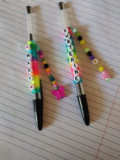 two pens sitting on top of a piece of lined paper with words written in them