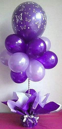 purple and white balloons in a vase on a table