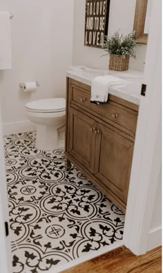 a white toilet sitting in a bathroom next to a wooden cabinet under a mirror on top of a tiled floor