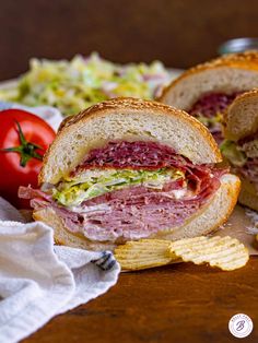 a sandwich cut in half sitting on top of a table next to crackers and tomatoes