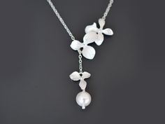 "** Free gift wrapping! - Each jewelry comes in Beautiful Gift Box! ** ** Free greeting card! - Please add your message on note box when you check out ** Orchid flower and Pearl Silver lariat necklace - Orchid necklace, Flower necklace, Pearl necklace, Silver necklace, Lariat necklace, Wedding jewelry, Bridal necklace, Anniversary   A gorgeous lariat made with white gold plated over brass orchid flowers and 8mm Swarovski pearl with white gold plated over a brass chain and clasp to finish this be White Lariat Drop Necklace For Gift, Elegant Flower Pendant Necklace For Bridesmaid Gift, Wedding Necklace With Adjustable Chain And Flower Pendant, Handmade White Lariat Necklace As Gift, Pendant Flower Necklace For Wedding, Handmade Elegant Drop Necklace For Weddings, Elegant Adjustable Flower Necklace For Wedding, Elegant Wedding Flower Necklace With Adjustable Chain, Delicate White Drop Necklace For Gift