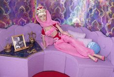 a barbie doll sitting on top of a purple couch