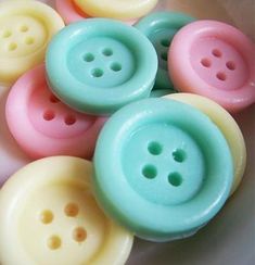 several pastel colored buttons in a white bowl