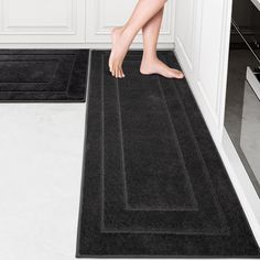 a person standing on a black rug in the middle of a kitchen