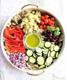 a bowl filled with different types of vegetables and sauce on top of it, sitting on a white surface