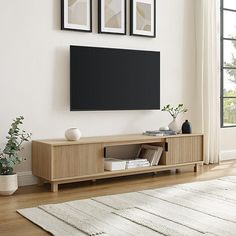 a living room with a large flat screen tv mounted on the wall above a wooden entertainment center