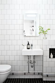 a white bathroom with black and white tile on the floor, sink, toilet and mirror