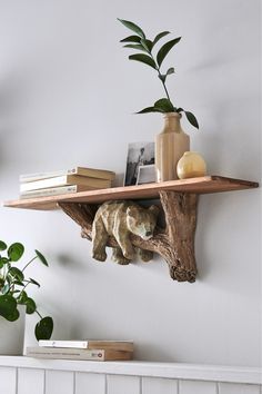 a wooden shelf with books, vases and other items on it next to a white wall