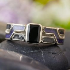 This handmade engagement ring is the perfect blend of elegant and alternative styles. Crafted with platinum and featuring obsidian stone and crushed amethyst inlay, this piece is finished with milgrain edges for a classic twist. Make a statement with this timeless black ring. RING LAYOUT Ring Width: 6 mm Ring Sleeve: Platinum Ring Profile: Custom - Twist With Milgrain Ring Metal Finish: Polished 0.75 mm Platinum 1.5 mm Partial Crushed Amethyst 0.75 mm Platinum 0.75 mm Platinum 1.5 mm Crushed Bla Handmade Engagement Ring, Jewelry By Johan, Milgrain Ring, Engraved Wedding Rings, Black Engagement Ring, Handmade Engagement Rings, Obsidian Stone, Alternative Style, Black Ring