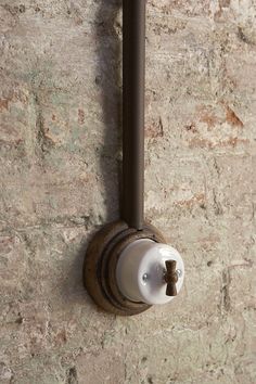 a wall mounted toilet paper dispenser on a stone wall with rusted metal handles